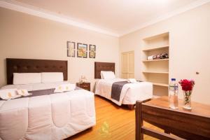 ein Schlafzimmer mit 2 Betten und einem Tisch mit Blumen in der Unterkunft Hostal Virreinal AQP in Arequipa
