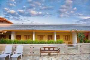 a house with chairs and a bench in front of it at Pousada Pôr do Sol in Cunha