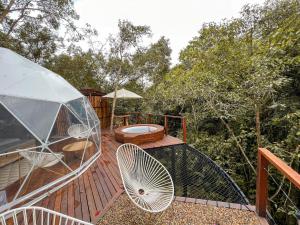 una terraza de madera con sillas, mesa y sombrilla en Solana Glamping, en Pereira