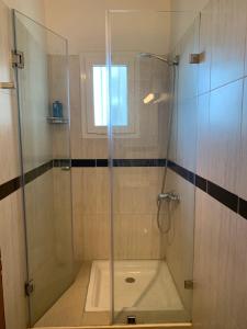 La salle de bains est pourvue d'une douche avec une porte en verre. dans l'établissement Au Bord du palmier, à Rabat