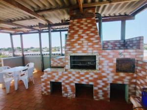 a brick fireplace on a patio with a table and chairs at HAPPY HOSPEDAGENS in Cascavel