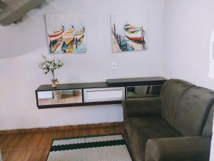 uma sala de estar com um sofá e pinturas na parede em HAPPY HOSPEDAGENS em Cascavel