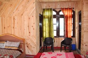 a bedroom with a bed and two chairs and a window at Olive Garden Classic in Tosh