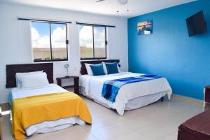 two beds in a room with blue walls and windows at Ocean view apartment, best beach area, 3 bedrooms in Cancún