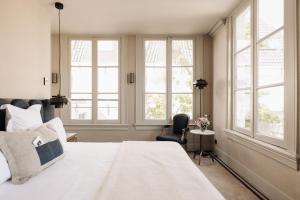 a bedroom with a large white bed and windows at Hotel 717 in Amsterdam