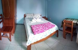Una cama pequeña con una manta rosa y blanca. en Hospedaje Franco-Peruano El Tambito en Sauce
