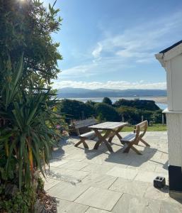 a picnic table and benches on a patio overlooking the water at Seaview Cottage in Aberdyfi