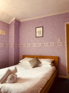 a bedroom with a white bed with purple walls at 'Melrose' at stayBOOM in Lancaster