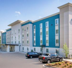 ein großes Gebäude mit auf einem Parkplatz abgestellten Autos in der Unterkunft Extended Stay America Select Suites - Charlotte - Northlake in Charlotte