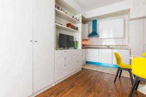 a kitchen with white cabinets and a table and yellow chairs at Apartamento Súper Céntrico in Málaga +14 photos