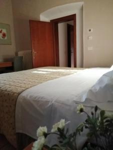 1 dormitorio con 1 cama con sábanas blancas y flores en B&B La Giara di Assisi, en Asís