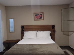 a bedroom with a large bed with a wooden headboard at Pousada Éden - Conforto, Imersão e Natureza in Sao Jorge