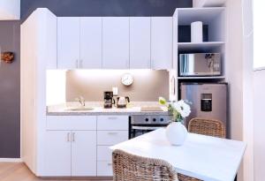 メキシコシティにあるROMÁNTICO Junto a Bellas Artes Centro Históricoの白いキャビネットと花瓶付きのテーブルが備わるキッチン