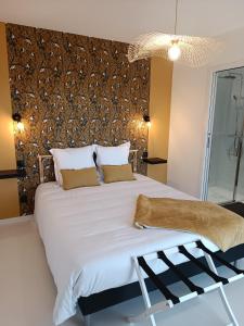 a bedroom with a large white bed with a wall at Maison Bailly in Ducey