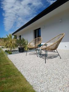 two chairs sitting on a gravel patio next to a house at Maison Bailly in Ducey