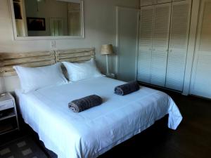 a bedroom with a large white bed with two towels on it at Double Room - Robberg in Plettenberg Bay