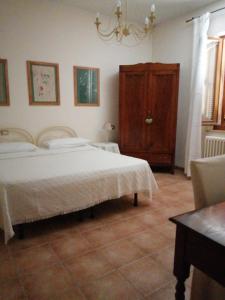 1 dormitorio con cama blanca y armario de madera en B&B La Giara di Assisi, en Asís