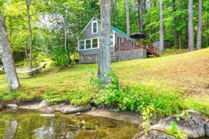 a house on a hill with a pond in front of it at Loon Cove in Waterville