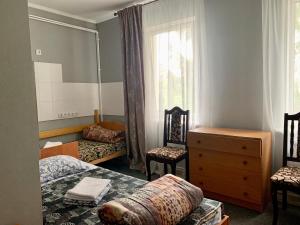 a bedroom with a bed and two chairs and a dresser at Мини-гостиница Три Коня in Pereyaslav