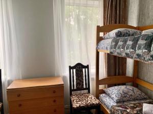 een slaapkamer met een stapelbed, een stoel en een raam bij Мини-гостиница Три Коня in Pereiaslav-Khmelnytskyi