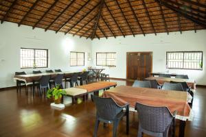 uma sala de jantar com mesas, cadeiras e janelas em The Nest bettathur, Coorg em Madikeri