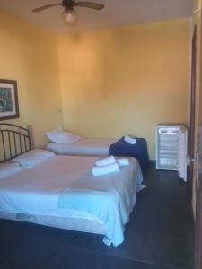 sypialnia z 2 łóżkami i wentylatorem sufitowym w obiekcie Recanto Saqua w mieście Saquarema