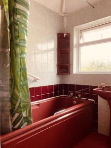 a red bath tub in a bathroom with a window at 'Melrose' at stayBOOM in Lancaster