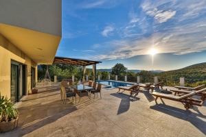 eine Terrasse mit einem Tisch, Stühlen und einem Pool in der Unterkunft Luxury Villa Elena in Primorski Dolac