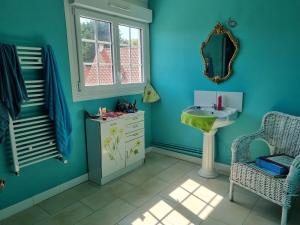 een blauwe badkamer met een wastafel en een spiegel bij Yassmine in Audinghen