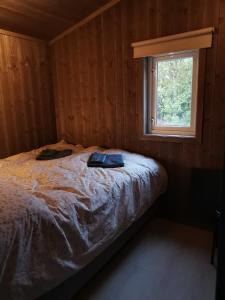 a bed in a wooden room with a window at Flott hytte sentralt i Hallingdal in Ål