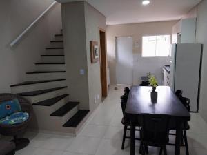a kitchen and dining room with a table and a staircase at LINDO SOBRADO GUARUJÁ in Guarujá