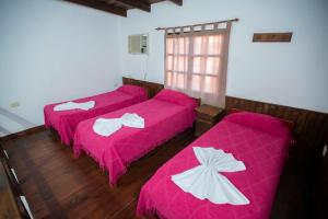 três camas num quarto com capas cor-de-rosa em LOS HELECHOS II em Puerto Iguazú