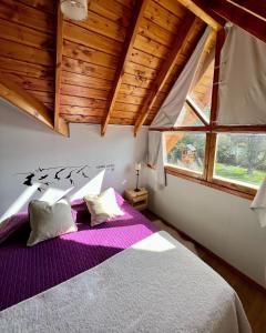 a bedroom with a large bed with purple sheets at La Cabaña del 5 in San Carlos de Bariloche