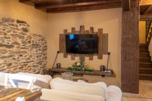 a living room with a couch and a tv on a wall at Las Morales Casa Rural 