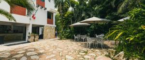 a patio with tables and chairs and an umbrella at Hotel Cañada Internacional in Palenque