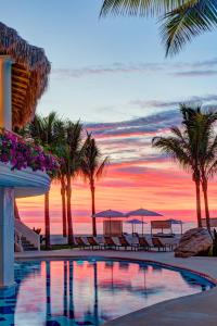 un complejo con piscina con palmeras y puesta de sol en Mar del Cabo By Velas Resorts en San José del Cabo