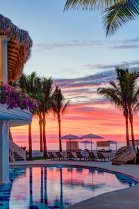 a resort swimming pool with palm trees and a sunset at Mar del Cabo By Velas Resorts in San José del Cabo