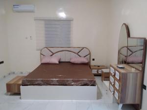 ein Schlafzimmer mit einem Bett und einer Holzkommode in der Unterkunft النسيم Nessim in Nouakchott