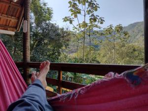 a person laying in a hammock looking out at the mountains at Bangalô Boa Ventura in Lumiar