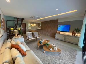 ein Wohnzimmer mit Sofa und Fernseher in der Unterkunft Casa Luxo com piscina privativa próximo a Igrejinha - Com colaboradora e enxoval in Praia dos Carneiros