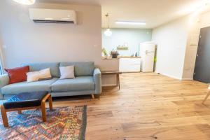 a living room with a blue couch and a kitchen at נופש ליד הים בת גלים in Haifa