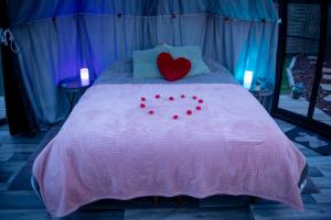 Cama con almohada de corazón y almohadas rojas en Thudi-nids en bulles en Gozée