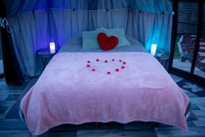 een bed met een hartkussen en rode kussens bij Thudi-nids en bulles in Gozée