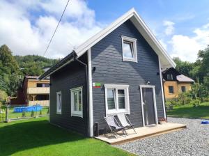 a black house with a chair in the yard at Domek na Blejchu in Wisła