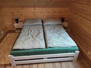 a small bed in a room with wooden walls at Domek na Blejchu in Wisła