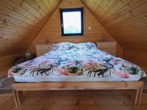 a bed in a wooden cabin with a comforter on it at Domki Kamienna4 in Gersdorf