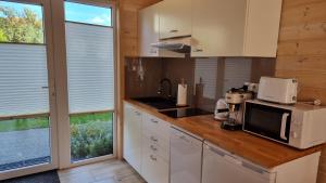 a kitchen with white cabinets and a counter with a microwave at DOMKI ZACHÓD SŁOŃCA w Ustroniu Morskim in Ustronie Morskie