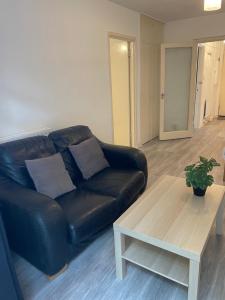 a living room with a black leather couch and a coffee table at Central London Serviced Apartment near Borough station SE1 in London