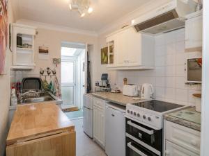 a kitchen with white cabinets and a sink and a stove at Greystones in Newton Stewart