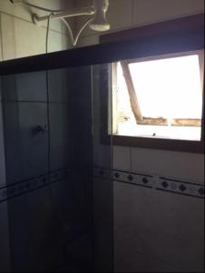 a bathroom with a glass shower with a window at Kitbox PDR in Garopaba